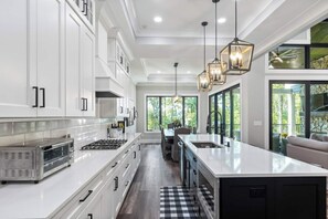 A modern kitchen with white cabinetry, a central island, and pendant lighting.