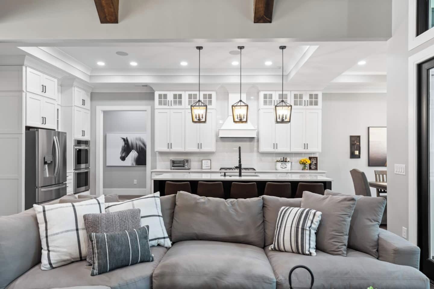 A modern kitchen with white cabinets, stainless steel appliances, and pendant lighting.