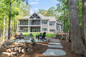 A two-story house with a covered patio, outdoor seating, and a stone pathway leading to the entrance.