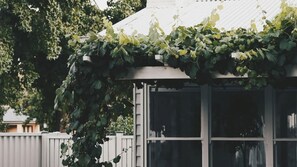 Une maison à l’extérieur blanc, avec une fenêtre, et une clôture blanche en arrière-plan.