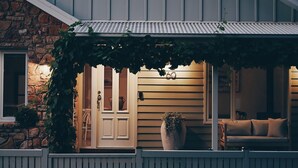 Een stenen gebouw met een veranda, een witte deur en het cijfer '60' op de muur.