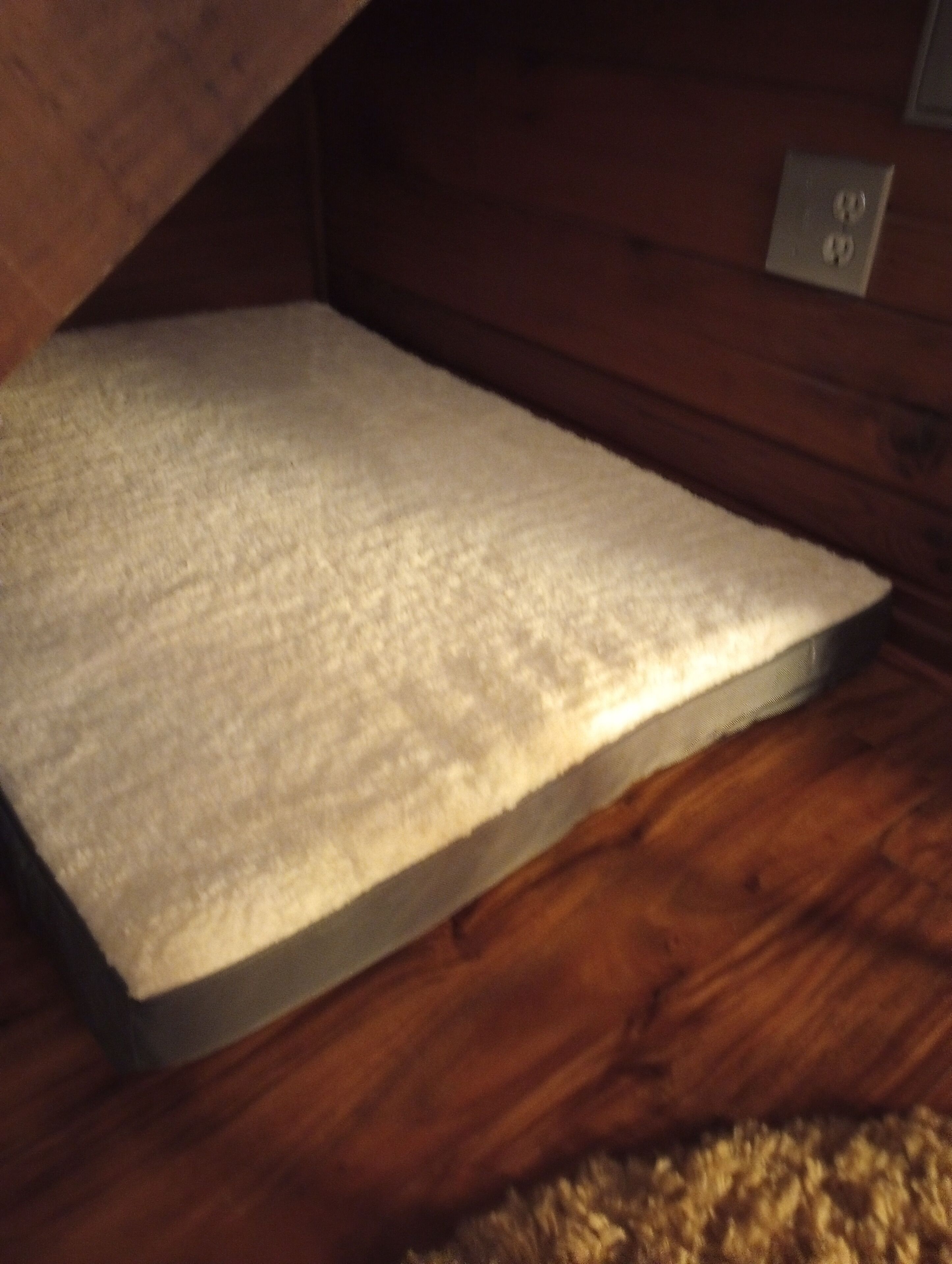 A wooden floor with a white textured mat.