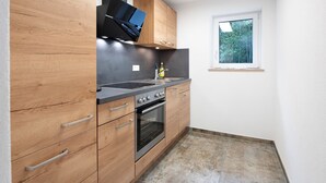 Una cucina moderna con mobili in legno, forno integrato e una finestra che offre luce naturale.