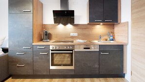 A modern kitchen with a built-in oven, a coffee machine, and a sink. - Ferienwohnung Rothirsch, 45 qm, 1 Schlafzimmer, 1 Schlafsofa, max. 4 Personen (Höchenschwand)