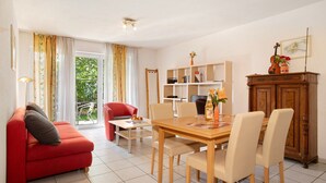 Un comedor con una mesa de madera, sillas, un sofá rojo y una estantería.