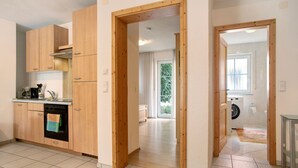 Una cocina con armarios de madera, horno empotrado y ventana.
