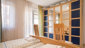 Un dormitorio con una cama, un armario de madera y una silla.