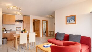 Un espacio habitable compacto con comedor, kitchenette y un sofá rojo.