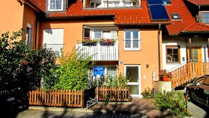 A two-story building with a balcony, a wooden fence, and a car parked in front. - Maisonette Aparment 3, 75 qm, 2 bedrooms, max. 5 people (Lindau am Bodensee)
