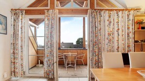 A room with a wooden ceiling, a dining table with chairs, a window with curtains, and a small table with a vase. - Maisonette Aparment 3, 75 qm, 2 bedrooms, max. 5 people (Lindau am Bodensee)