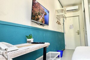 A reception area with a desk, phone, keyboard, and a TV displaying a scenic view. - 3C Residence (Pagedangan)
