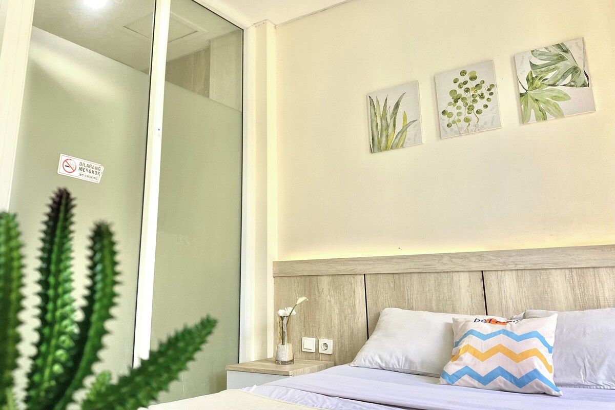 Une chambre d’hôtel avec un lit, une table de chevet ornée d’un vase et des œuvres d’art murales.