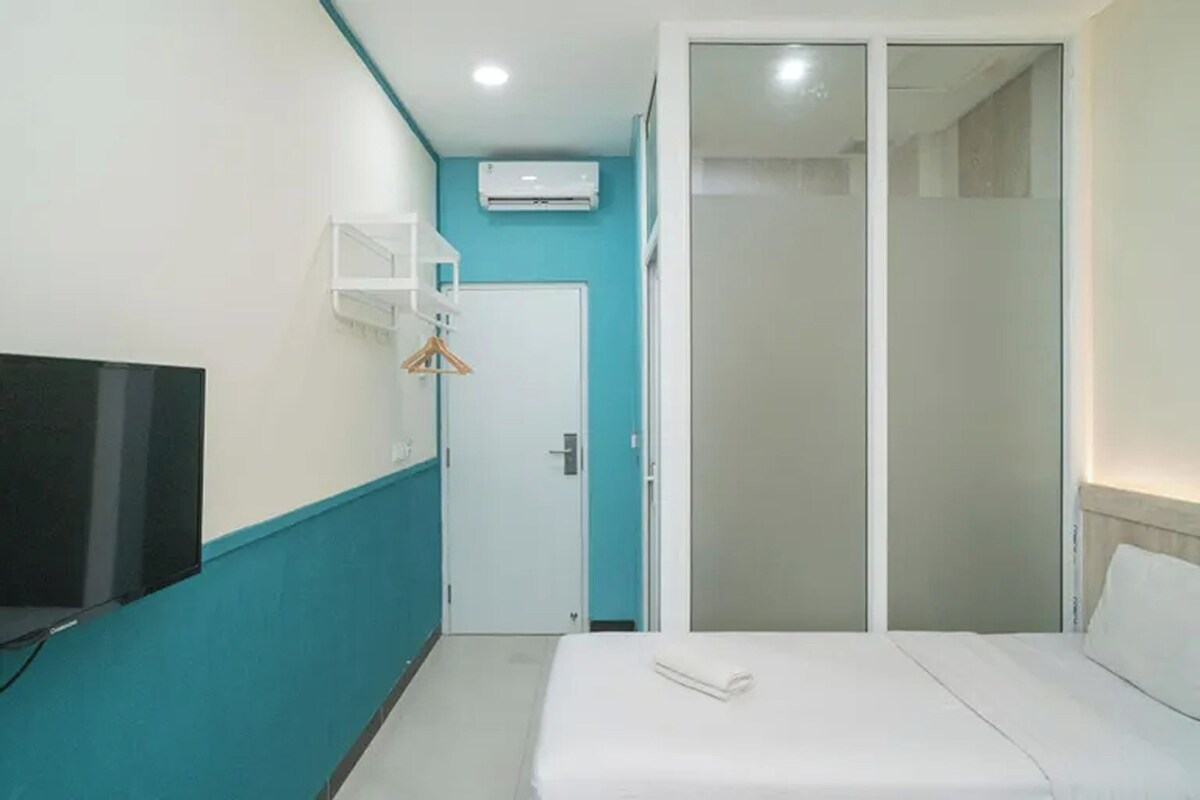 A hotel room with a bed, a TV, a wardrobe, and an air conditioning unit.