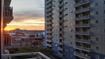 A high-rise residential building with multiple balconies and a sunset in the background.