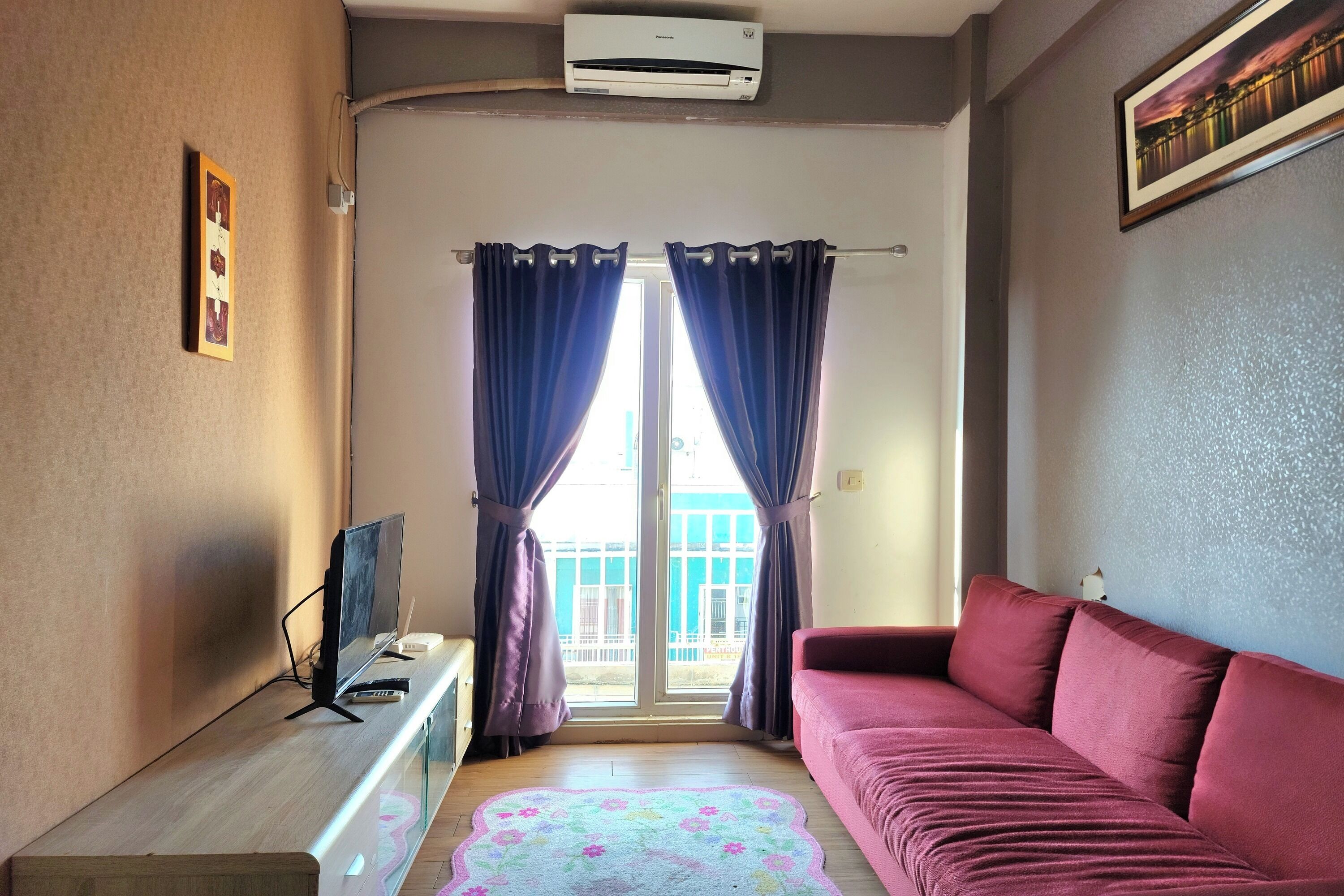 A living room with a sofa, a TV, and a window with curtains.