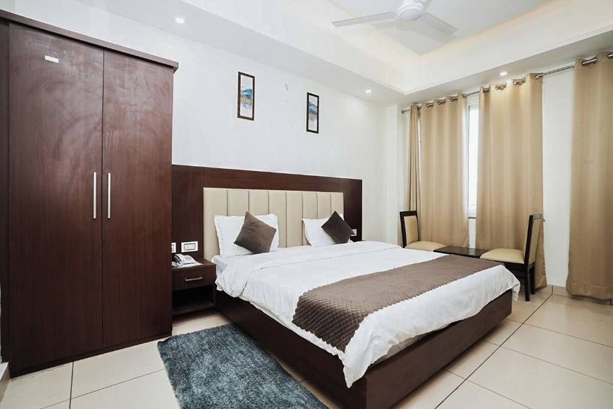 A bedroom with a large bed, a wardrobe, a desk, and a chair.