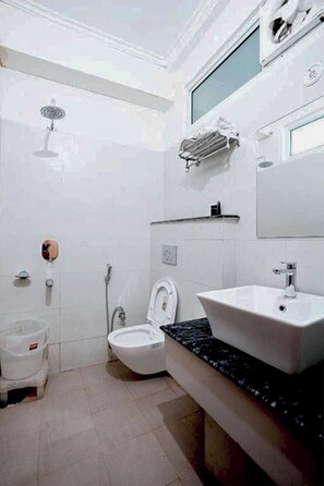 A bathroom with a white toilet, a sink, and a shower. - Hotel The 7 Seas (Rishikesh)