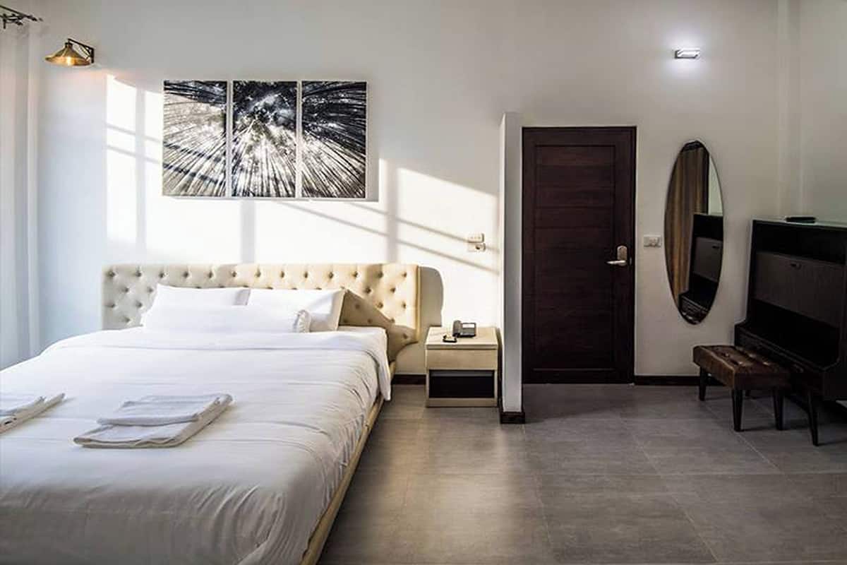 A hotel room with a large bed, a bedside table, a TV, and a door.