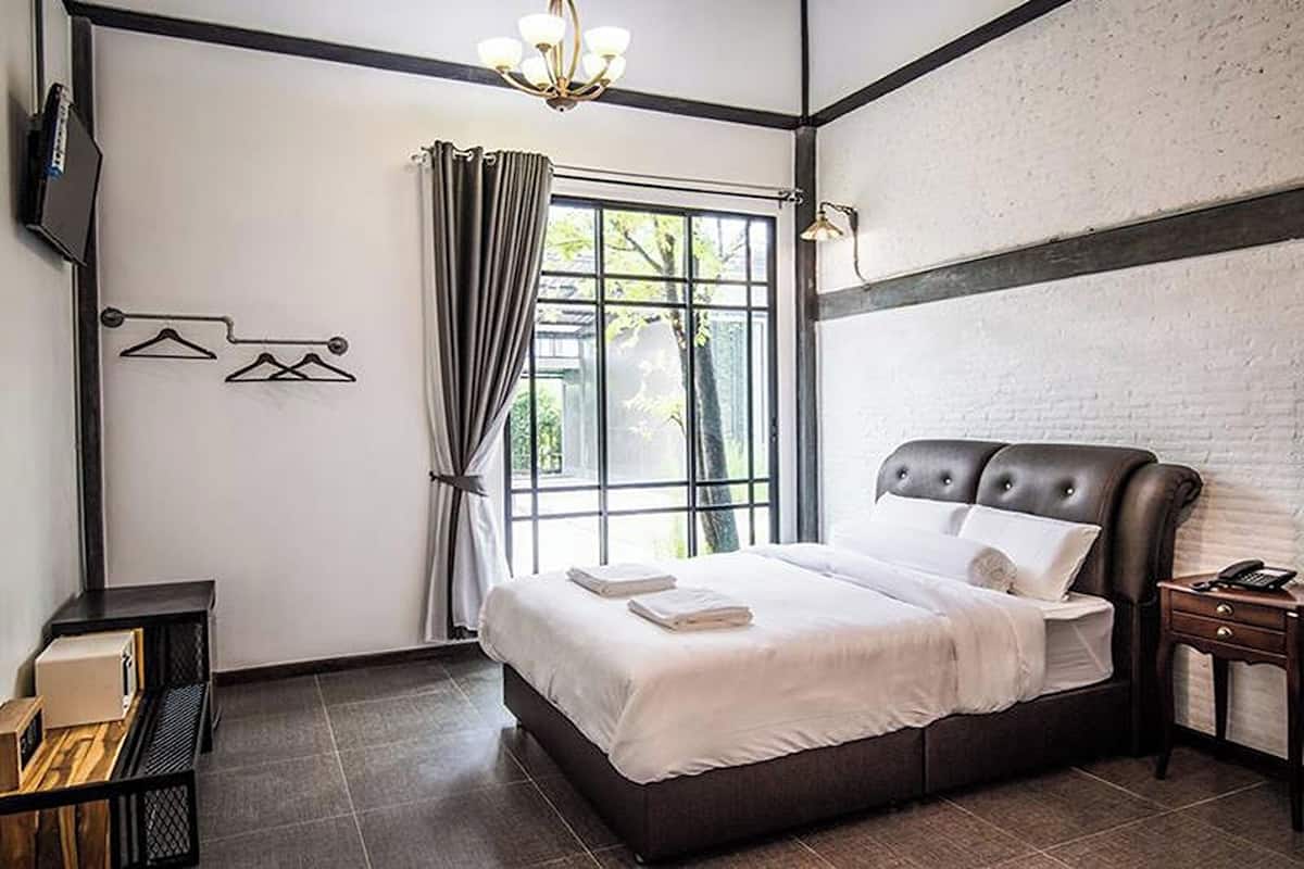 A modern hotel room with a large bed, a TV mounted on the wall, and a window with curtains.