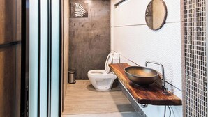 Une salle de bain moderne comprenant des toilettes, un lavabo avec un plan de travail en bois, un miroir et un mur à texture.