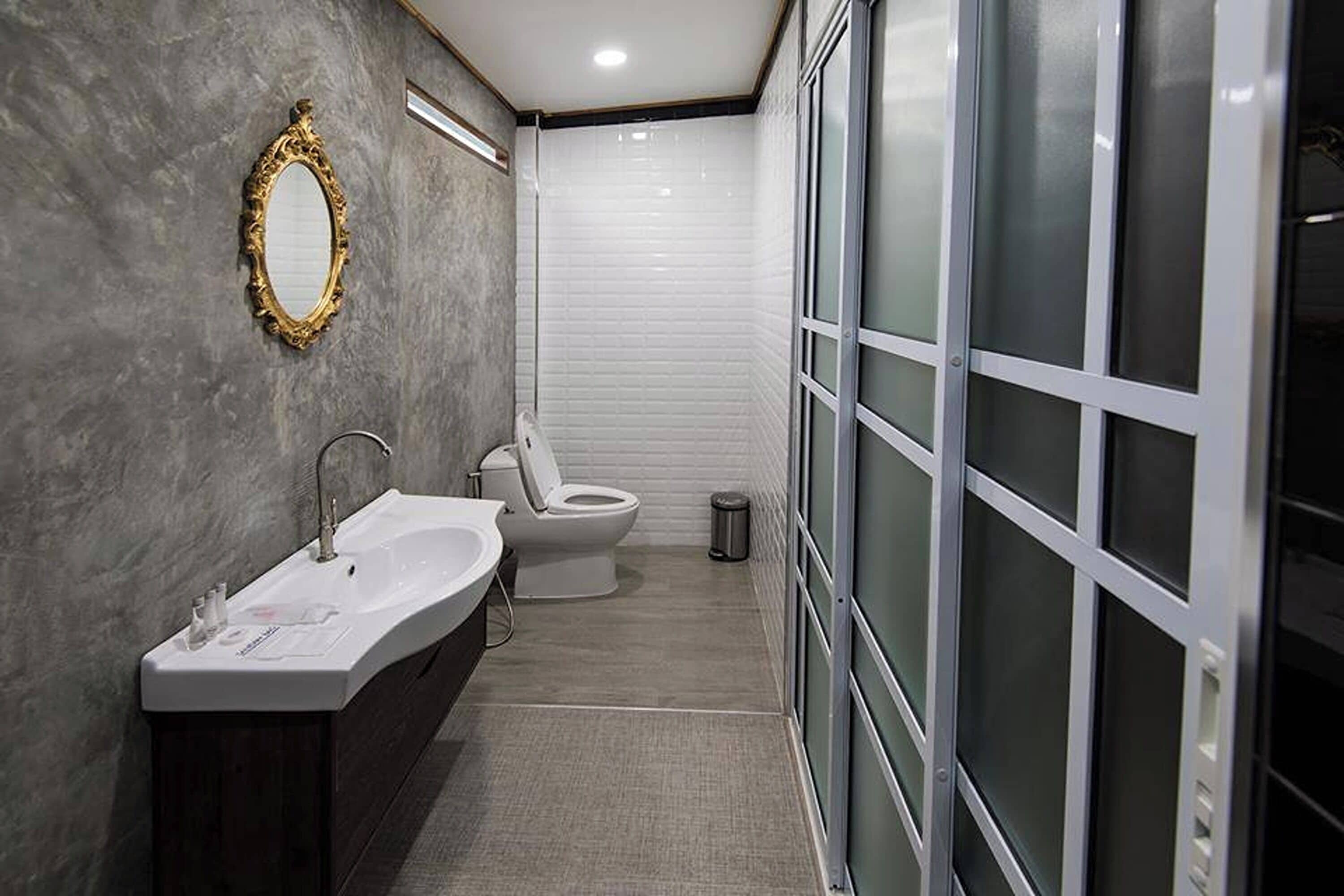 Un baño moderno con un espejo grande, un lavabo y un inodoro.