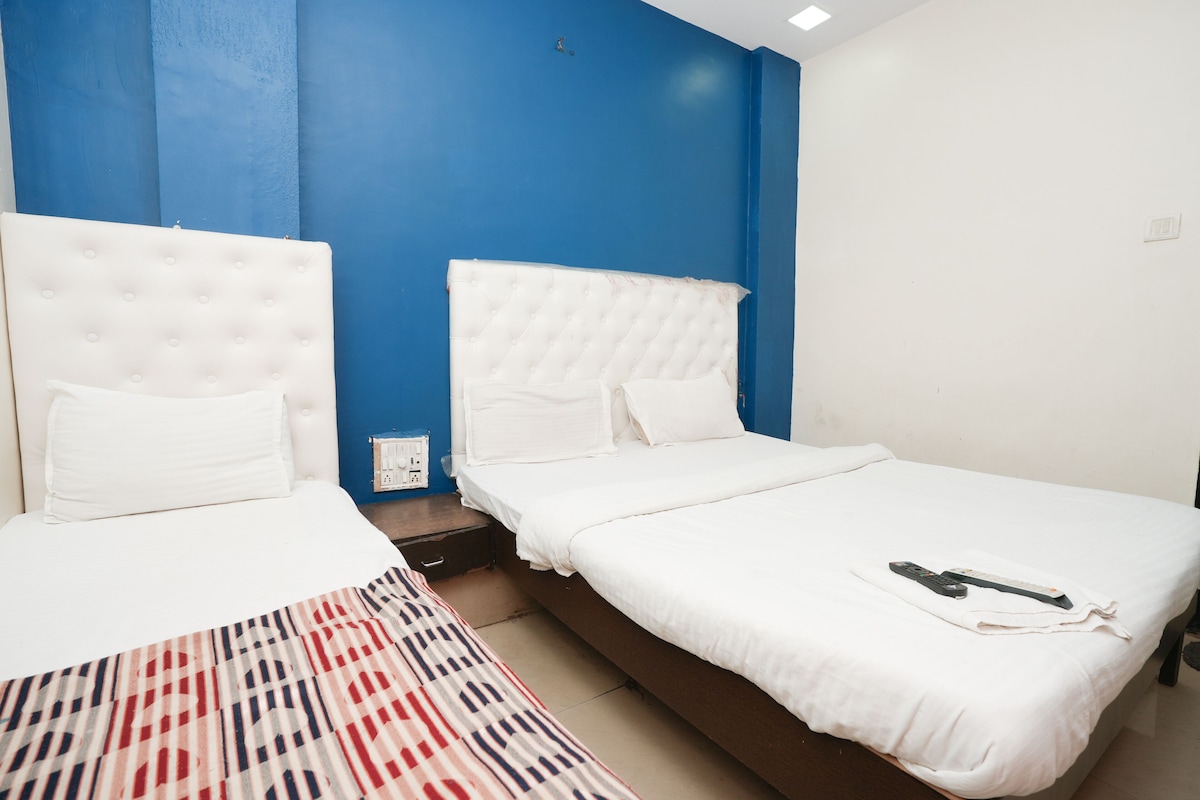A hotel room with two beds, a patterned rug, and a blue accent wall.
