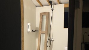 Une petite salle de bain avec une douche, des toilettes et un distributeur de savon.