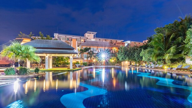 A hotel with a swimming pool, palm trees, and a well-lit exterior. - Eastiny Resort & Spa (Pattaya)