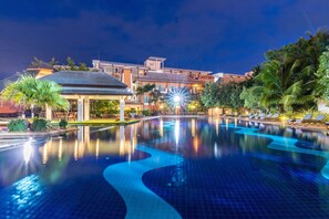 A hotel with a swimming pool, palm trees, and a well-lit exterior. - Eastiny Resort & Spa (Pattaya)