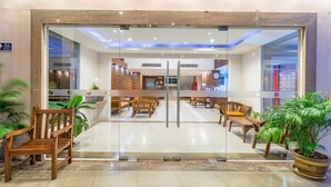 A modern lobby with a glass partition, wooden benches, and potted plants. - Eastiny Resort & Spa (Pattaya)