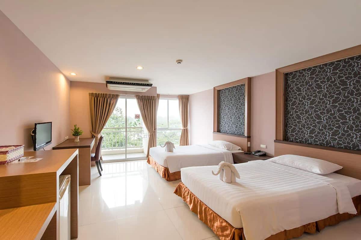 A hotel room with two beds, a desk, a TV, and a large window with curtains.