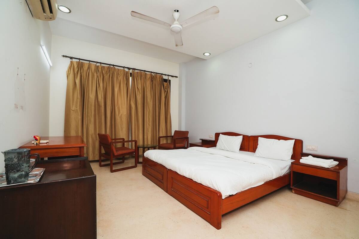 A bedroom with a wooden bed, a desk, a chair, a nightstand, and a ceiling fan.