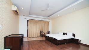 A bedroom with a bed, a desk, a chair, a ceiling fan, and an air conditioning unit. - Home 92 (Noida)