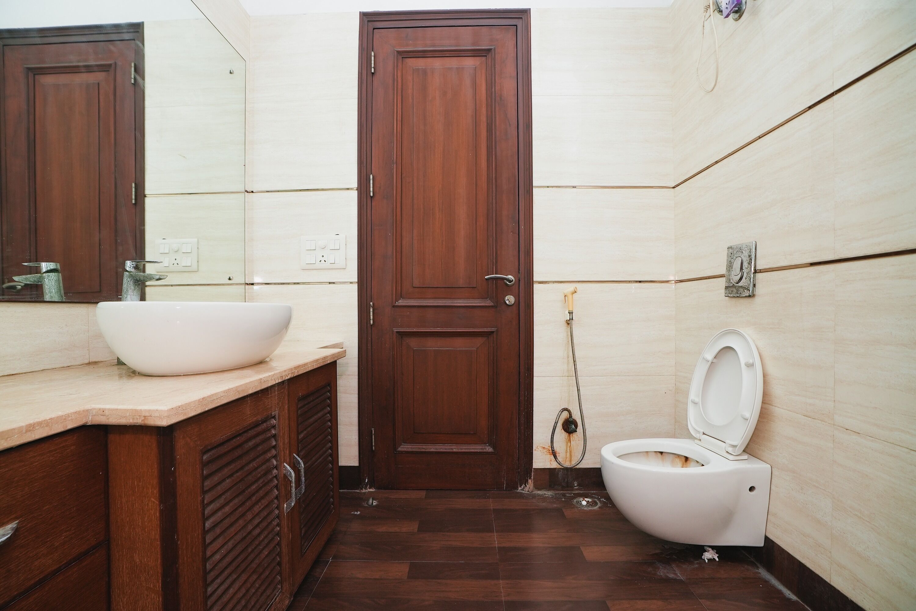 A bathroom with a wooden door, a white sink, and a toilet.