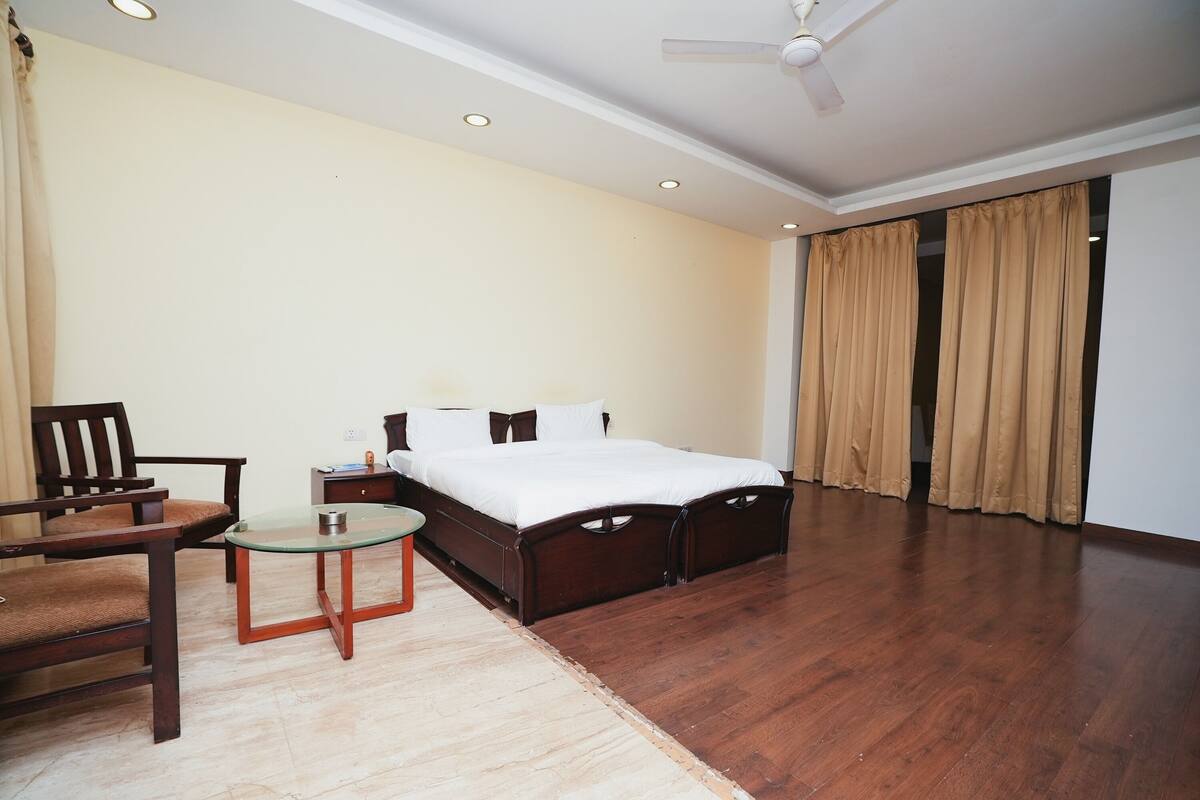 A bedroom with a bed, a chair, a small table, and a ceiling fan.