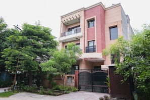 Stunning multi-story building with a flat roof and balcony, set amidst lush greenery.