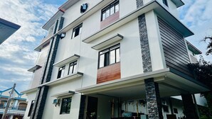 Un edificio moderno de varios pisos con techo plano, ventanas grandes y un balcón.
