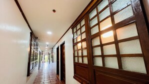 Un pasillo con suelo de baldosas, ventanas de madera con vidrio esmerilado e iluminación empotrada en el techo.