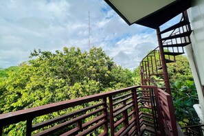 Uma varanda com vista para um verde exuberante e uma torre de comunicação ao longe.