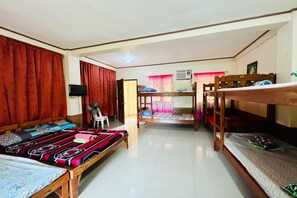 A dormitory room with bunk beds, a television, a fan, and a window with curtains. - Mc'S L Transient House (Vigan)