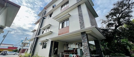 Una casa moderna de dos pisos con techo plano, ventanas grandes y un porche cubierto.