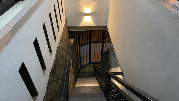 A staircase with a light fixture at the top, a metal railing, and a wall with rectangular cutouts. - Villa Buana Graha Syariah (Lembang)