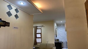 A living room with a beige sofa, a small table, and a decorative wall with geometric patterns. - Villa Buana Graha Syariah (Lembang)
