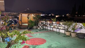 A rooftop garden with potted plants, a wooden gazebo, and a red circular mat. - Villa Buana Graha Syariah (Lembang)