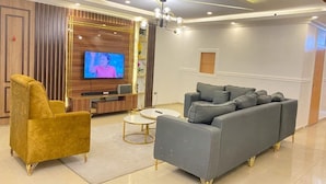 A modern living room with a sofa, armchair, TV, and decorative elements. - Deluxe Apartment (Lagos)