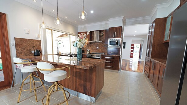 A modern kitchen with a central island, bar stools, stainless steel appliances, and wooden cabinets. - Hallam 5BRM Rental Entire House (Hallam)