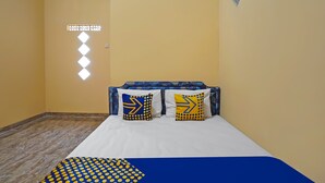 Ein Zimmer mit einem Bett, zwei Kissen mit Pfeilmuster, einer strukturierten Wand und einem kleinen Fenster.