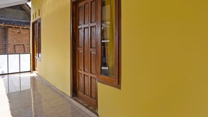 Ein Korridor mit gelber Wand, Holztür und Fliesenboden.