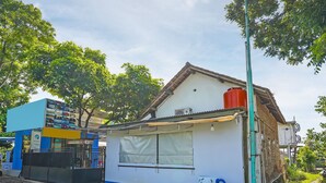 Ein kleines Gebäude mit weißer Fassade, rotem Dach und blauer Markise.