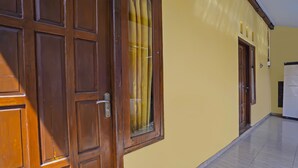 Ein Korridor mit einer Holztür und einem Fenster mit gelben Vorhängen.